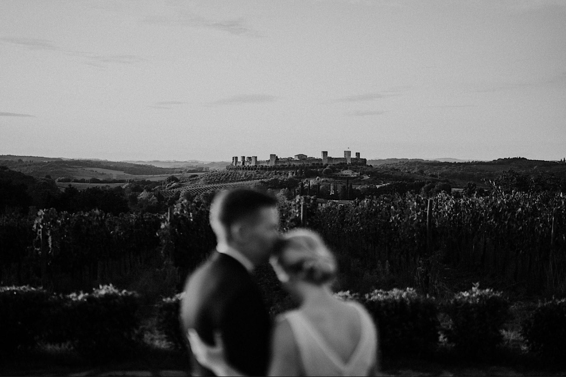 Bride and groom embracing with a romantic view of Monteriggioni, Tuscany in the background